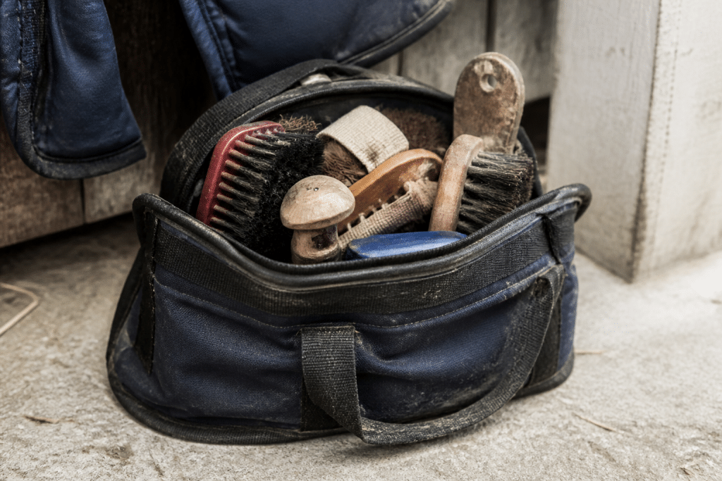 Sac ouvert contenant brosses, etrille et cure-pied chevaux